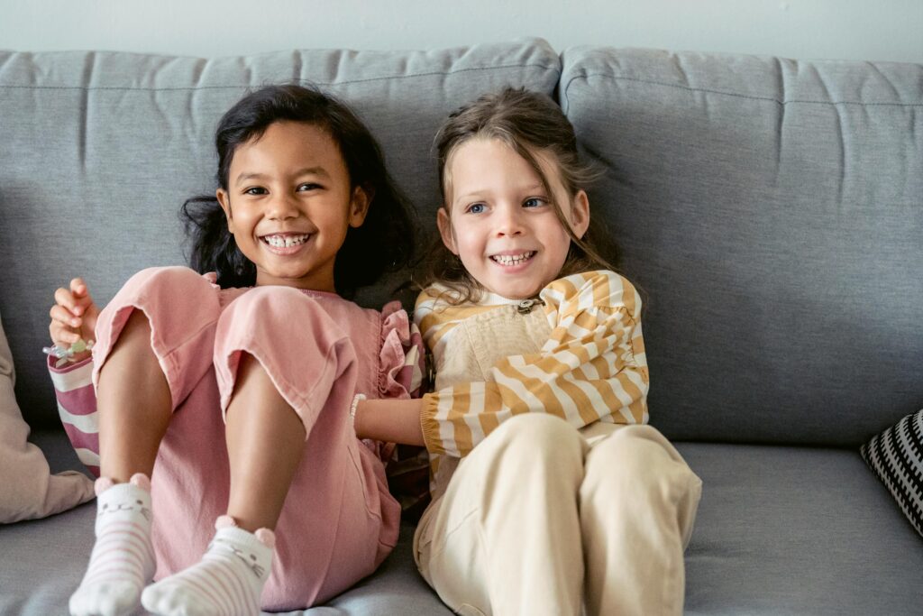 pexels-photo-7169660-7169660 Cheerful best multiracial friends in striped clothes interacting on couch in living room in house