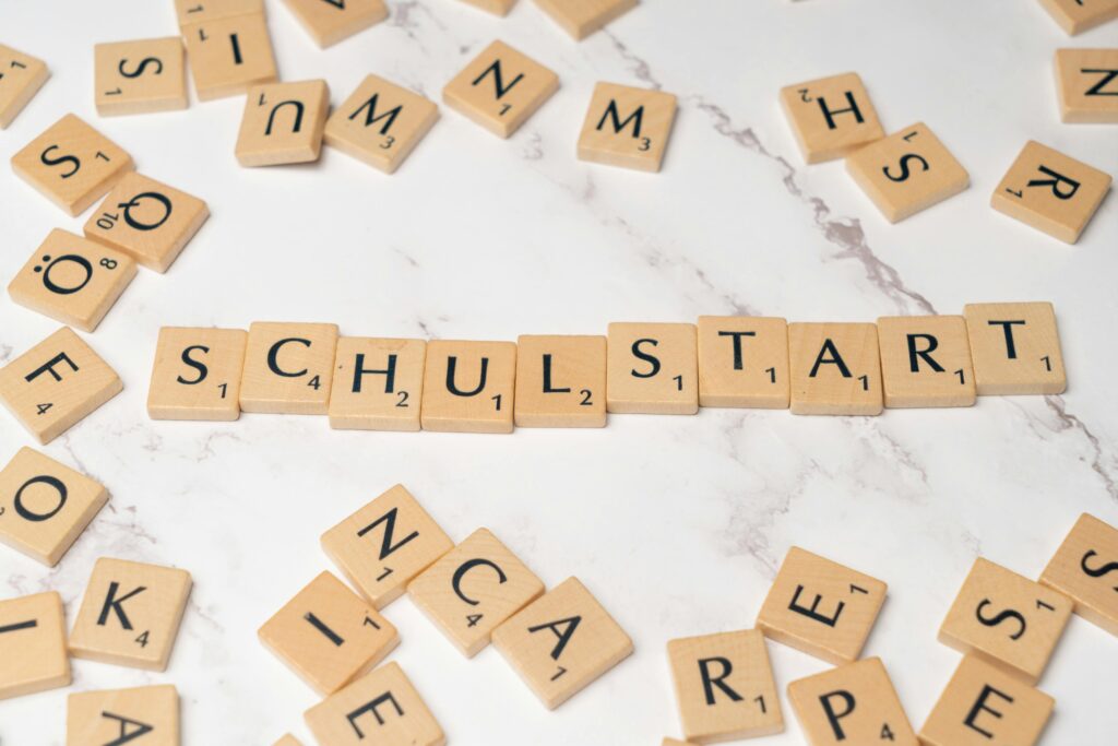 pexels-photo-18512875-18512875 Wooden tiles forming the word 'Schulstart' on a marble surface, symbolizing school beginning.
